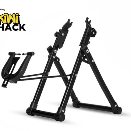 A black foldable bicycle repair and maintenance stand with a frame holder cradle on the front against a white background, featuring the "Kiwi Shack" logo in the upper left corner.