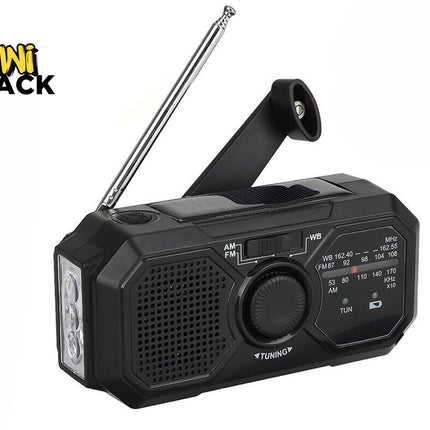 A black emergency weather radio featuring an extendable antenna, a hand crank, a built-in solar panel, a flashlight on the side, and a tuning dial, with a "Kiwi Shack" logo in the top left corner.