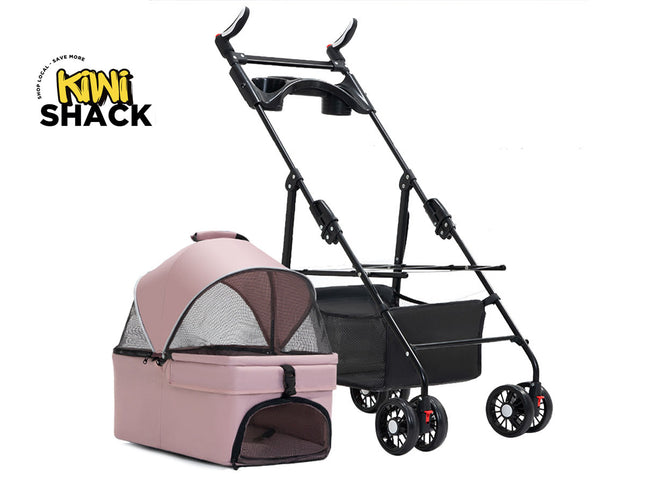 Pink and grey detachable pet carrier / bassinet with a mesh canopy and lower zipped mesh door, placed beside a black collapsible stroller frame with multi-wheel casters, a lower storage basket, and the Kiwi Shack logo watermark.
