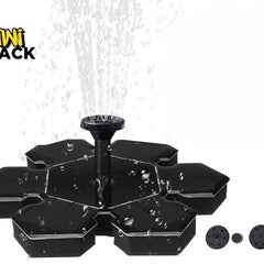 A black floating solar-powered water fountain with a central nozzle spraying water upward, shown with alternative spray heads lined up on the bottom right against a white background. A "Kiwi Shack" logo appears in the top-left corner.
