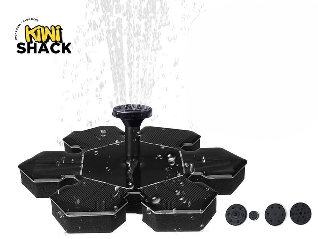 A black floating solar-powered water fountain with a central nozzle spraying water upward, shown with alternative spray heads lined up on the bottom right against a white background. A "Kiwi Shack" logo appears in the top-left corner.
