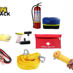 A comprehensive roadside emergency and safety kit laid out against a white background, including a red fire extinguisher, a blue reflective warning triangle case, a red "FIRST AID KIT" bag, heavy-duty jumper cables, a yellow tow strap with hooks, a tire repair set, a pair of work gloves, and a hand holding a yellow emergency escape hammer, with the "Kiwi Shack" logo in the upper left corner.