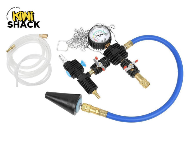 A cooling system pressure tester and vacuum purge refill kit featuring a circular pressure gauge, black manifold blocks with control valves, a blue hose with a conical rubber adapter, and a clear transparent fluid hose with brass fittings, with a "Kiwi Shack" logo in the top left corner.