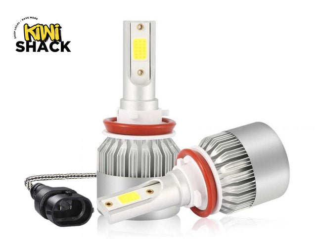pair of LED automotive headlights with silver metal cooling heat sinks, red O-ring seals, and a connected power plug cable, set against a white background with the "Kiwi Shack" logo in the top left corner.