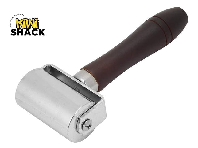 Heavy-duty steel wallpaper/laminate seam roller with a smooth cylindrical metal roller, side screw-fixed bracket, ergonomic turned dark wood handle with decorative groove rings, and the Kiwi Shack logo watermark.
