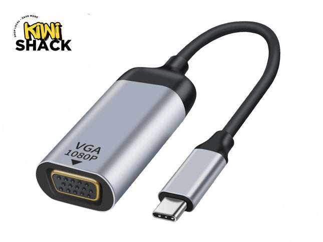 A silver and black USB-C to VGA adapter cable labeled "VGA 1080P" on the housing, connecting a female VGA port on the left to a male USB-C connector on the right, featuring a "Kiwi Shack" logo in the top left corner.