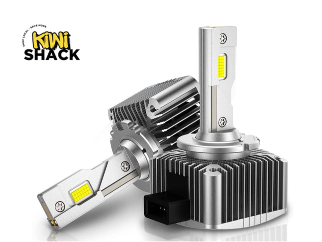 Two automotive LED headlight bulbs with silver heat sinks and yellow LED chips, shown on a white background with the Kiwi Shack logo in the top left.