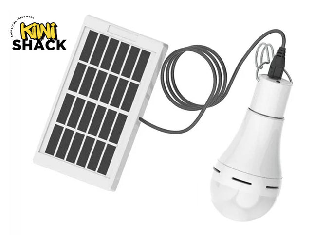 A portable solar-powered LED light bulb connected via cord to a small solar panel, featuring the "Kiwi Shack" logo in the top-left corner.