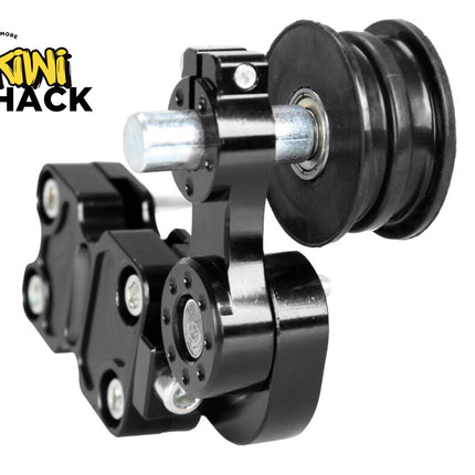 A black metal mechanical component with a grooved pulley wheel and mounting bracket against a white background, featuring the "Kiwi Shack" logo in the upper left corner.
