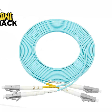 A coiled light blue LC-LC duplex fiber optic patch cable with gray connectors and protective dust caps, set against a white background. A "Kiwi Shack" logo appears in the top-left corner.