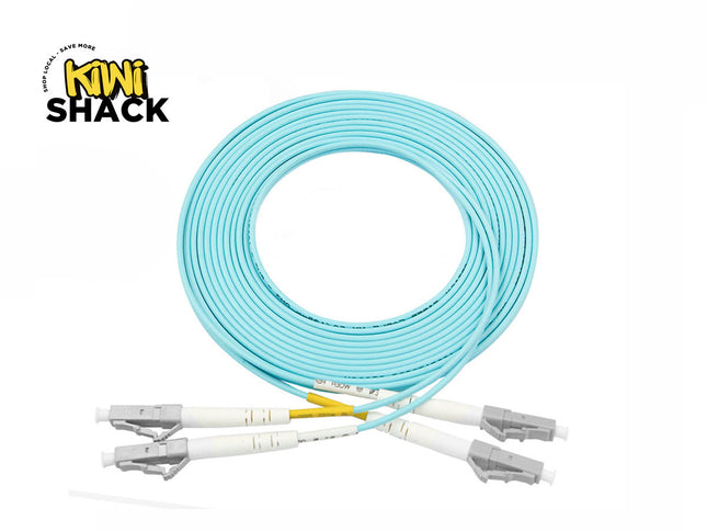 A coiled light blue LC-LC duplex fiber optic patch cable with gray connectors and protective dust caps, set against a white background. A "Kiwi Shack" logo appears in the top-left corner.