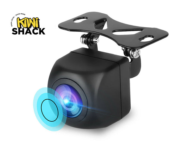 A black mini car rear-view backup camera with a mounting bracket, shown on a white background with a blue lens flare graphic and a Kiwi Shack logo in the top-left corner.