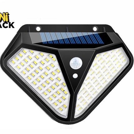 A trapezoidal solar-powered wall light featuring two angled multi-LED panels, a built-in motion sensor on the front center, and a small solar panel integrated into the top section against a white background, featuring the "Kiwi Shack" logo in the upper left corner.