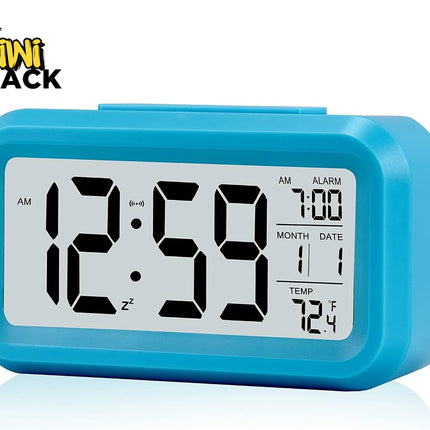 A bright blue digital desktop alarm clock featuring a large LCD screen with bold black numbers, an alarm time of 7:00, calendar month and date, temperature display in Fahrenheit, and a snooze icon against a white background, featuring the "Kiwi Shack" logo in the upper left corner.