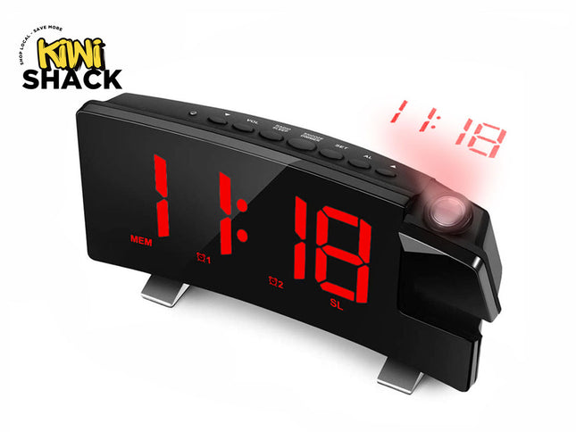 A curved black digital projection alarm clock featuring a large red LED time display and a rotating projector lens that casts the time onto a surface, featuring a "Kiwi Shack" logo in the top left corner.
