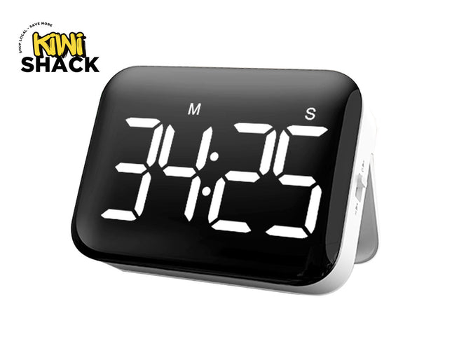 A black digital kitchen timer with a white LED display showing "34:25" and "M" and "S" labels above the digits, resting on a white stand against a plain background, with the "Kiwi Shack" logo in the top left corner.