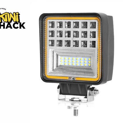A square LED work light with multiple spotlight lenses and an LED strip section, mounted on an adjustable metal bracket against a white background, with the "Kiwi Shack" logo in the upper left corner.