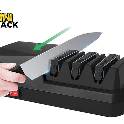 A black Kiwi Shack electric knife sharpener with three sharpening slots, shown with a hand holding a knife against it. A green arrow graphic points to the knife as it passes through the slots.