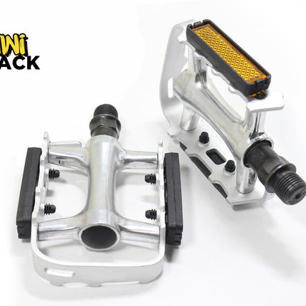A pair of silver bicycle pedals featuring threaded steel spindles, black rubber platform grips, and integrated orange reflectors against a white background, featuring the "Kiwi Shack" logo in the upper left corner.