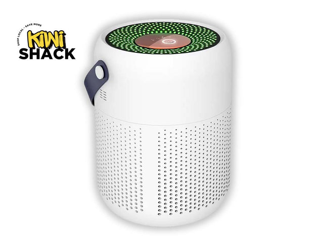 A white cylindrical portable speaker with a green LED ring on top and a dark blue carrying handle, shown on a white background with a Kiwi Shack logo in the top-left corner.