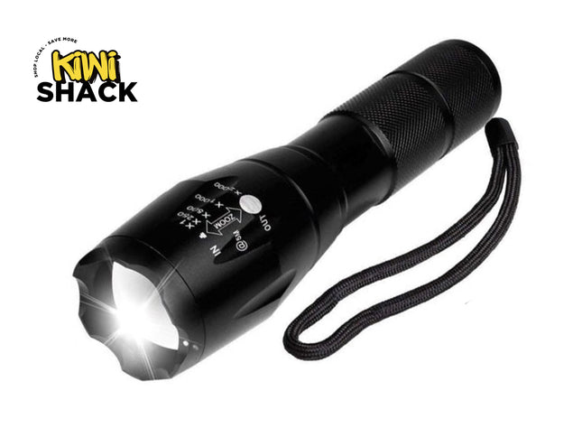 Black flashlight with visible light on a white background, featuring the Kiwi Shack logo.