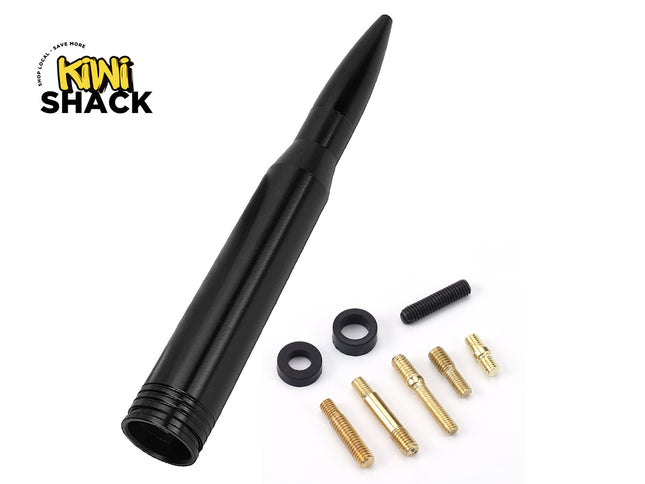 A black bullet-style car antenna with various brass mounting screws, threaded studs, and rubber washers arranged alongside it, featuring a "Kiwi Shack" logo in the top left corner.