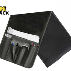 Black PU leather bedside/couch caddy organizer with multi-pocket front pouch holding a phone, remote, and pen, slip-in main pocket with white papers, and weighted flap, featuring Kiwi Shack logo in top left.