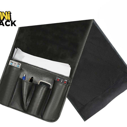 Black PU leather bedside/couch caddy organizer with multi-pocket front pouch holding a phone, remote, and pen, slip-in main pocket with white papers, and weighted flap, featuring Kiwi Shack logo in top left.