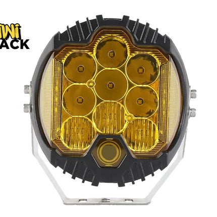 A round off-road LED work light with a black housing, amber yellow lenses, and a silver mounting bracket, shown on a white background with the Kiwi Shack logo in the top-left corner.