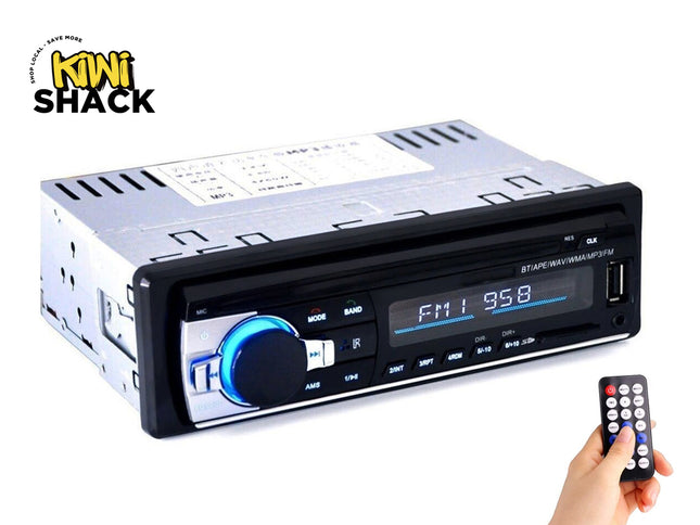 A single-DIN car stereo head unit with a digital display, glowing blue volume knob, USB port, and a small wireless remote control held in a hand, featuring the "Kiwi Shack" logo in the top-left corner.