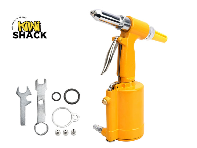 A bright yellow pneumatic air rivet gun with a chrome bit attachment, shown alongside included metal wrenches, washers, O-rings, and small fasteners on a white background. The Kiwi Shack logo is visible in the upper left.