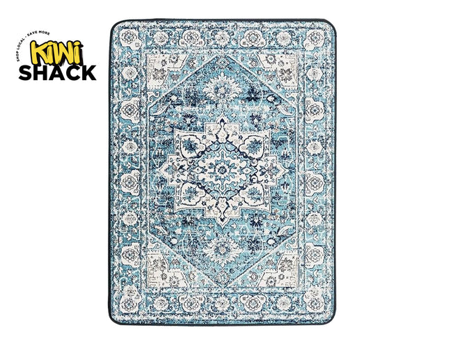 A rectangular area rug with a distressed traditional pattern in shades of blue, navy, and cream, shown flat against a white background with a Kiwi Shack logo in the top-left corner.