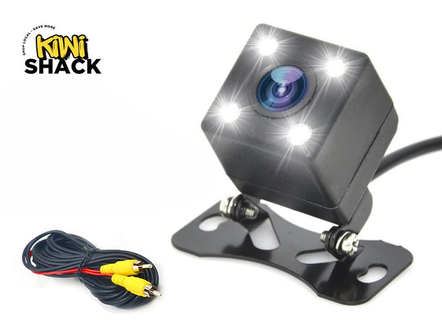 A compact black backup camera with four LED lights, an adjustable mounting bracket, and a video cable with yellow RCA connectors, featuring the "Kiwi Shack" logo in the top-left corner.