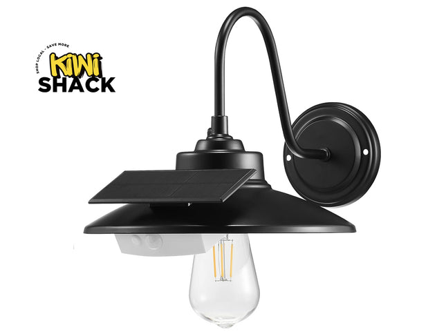 Black solar outdoor wall sconce with a curved gooseneck arm, a flat canopy mount, a small integrated solar panel, and a clear glass bulb, shown on a white background with the Kiwi Shack logo in the top-left corner.