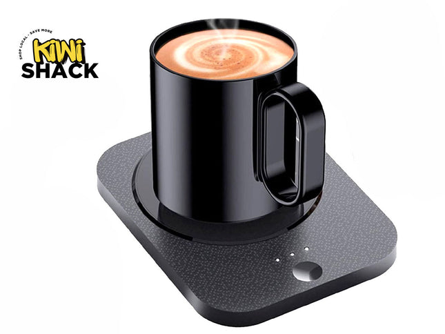 A black electric mug warmer base with a textured surface and power button, holding a black mug filled with steaming coffee, featuring a "Kiwi Shack" logo in the top left corner.
