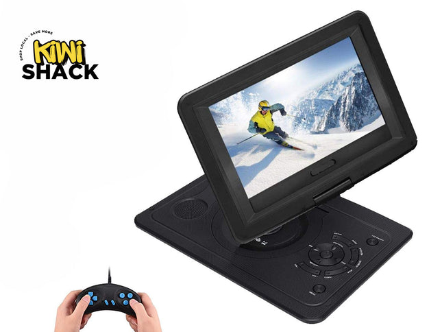 Black portable DVD player / multimedia player with an swiveling widescreen display showing a skier on a snowy mountain, built-in lower speaker, navigational directional control pad, and functional buttons on the base unit, accompanied by a small handheld game controller with blue buttons held by hands in the bottom left, and the Kiwi Shack logo watermark.