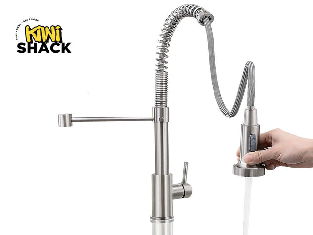 A stainless steel kitchen faucet with a flexible gooseneck sprayer and a side arm, shown with a hand holding the pull-out spout under running water. The Kiwi Shack logo is visible in the top left corner.