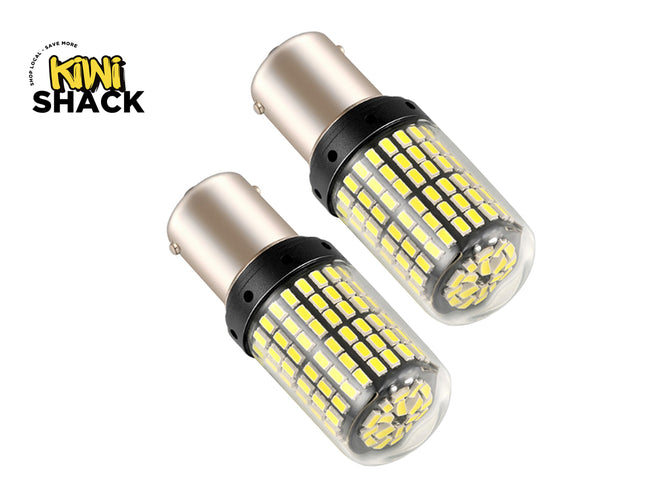 A pair of high-output automotive LED replacement bulbs featuring dense rows of yellow chips encased in protective transparent covers with metal bayonet bases, set against a white background. A "Kiwi Shack" logo appears in the top-left corner.