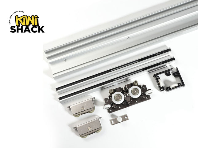 Heavy-duty sliding door track hardware set including extruded aluminum upper and lower tracks, tandem roller carriages, floor guides, and mounting brackets, with Kiwi Shack logo in top left.