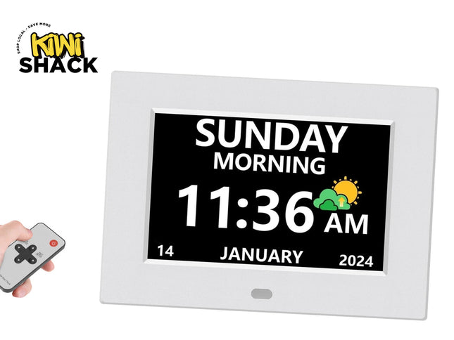 A white digital clock display with a black screen showing the time 11:36 AM and Sunday, January 14, 2024. A hand holding a small remote control appears in the lower left corner.