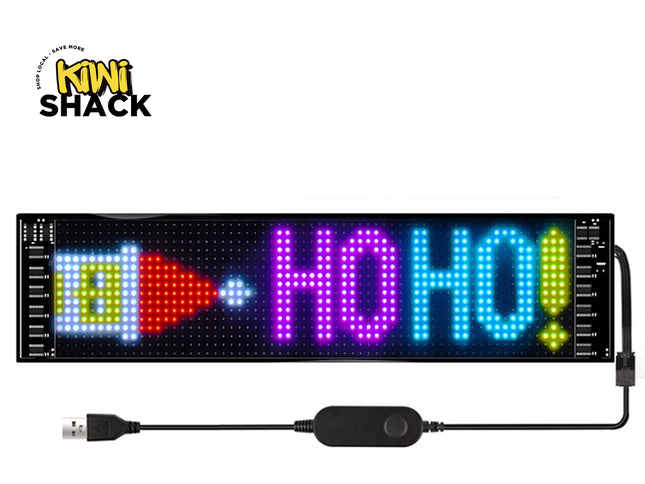 A 16x2 LED sign displaying 'HO HO!' in colorful lights, shown with its USB cable and controller on a white background with the Kiwi Shack logo.