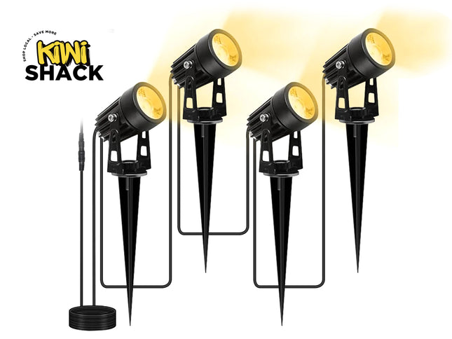 Four black outdoor landscape lights with stake mounts and a separate black power cord, shown on a white background with a yellow glow effect. The Kiwi Shack logo is visible in the top left.