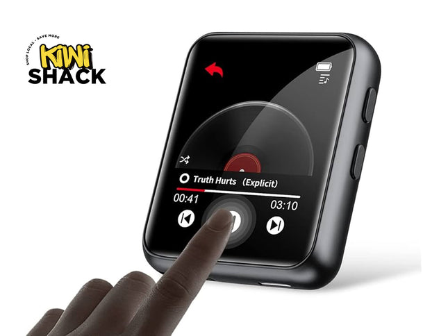 A black square digital media player with a glossy screen showing a music player interface, held by a hand pointing at the screen. The Kiki Shack logo is visible in the top left corner.