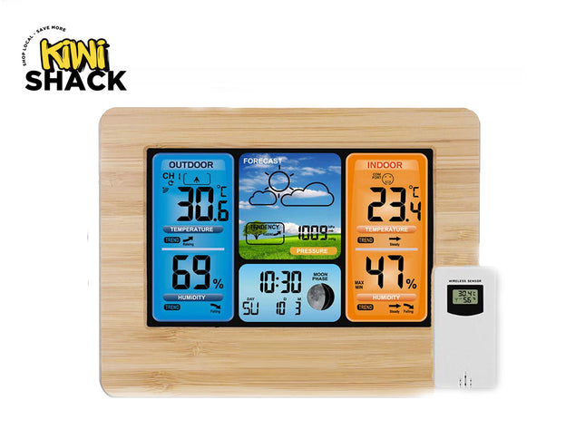 A wireless weather station featuring a light bamboo-grain frame, a color digital LCD display with outdoor and indoor temperature and humidity panels, weather forecast graphics, time, barometric pressure, and moon phase, accompanied by a separate white remote sensor, set against a white background. A "Kiwi Shack" logo appears in the top-left corner.