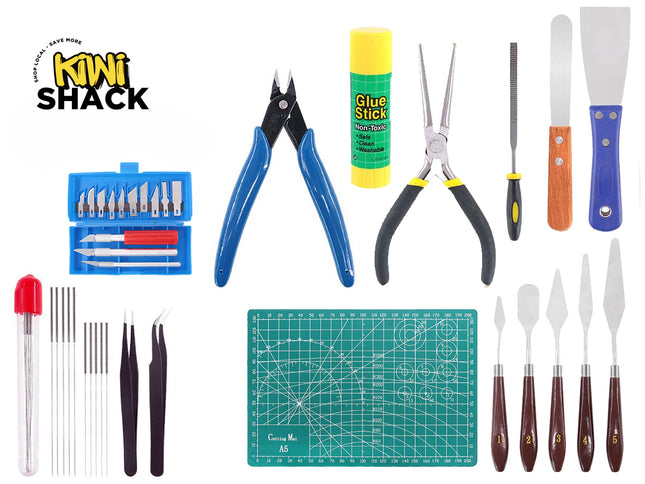 A comprehensive craft and hobby tool kit including an A5 green self-healing cutting mat, precision hobby knives with a storage case, wire cutters, needle-nose pliers, a glue stick, a small file, scrapers, tweezers, a set of fine files or needles, and an assortment of palette knives with wooden handles, set against a white background. A "Kiwi Shack" logo appears in the top-left corner.