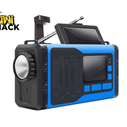 A portable emergency radio with a blue and black rugged design, featuring a built-in solar panel on top, a large front speaker, and control buttons on the side. The Kiwi Shack logo is visible in the top-left corner.