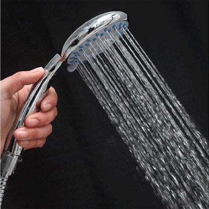 Hand holding a shower head with water flowing against a black background
