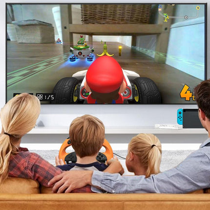 Family playing a racing video game on a Nintendo Switch console with a large screen displaying the game.