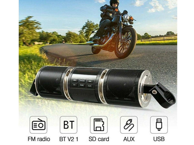 A black cylindrical portable Bluetooth speaker with silver accents and a clip, shown in front of a motorcycle riding on a road. Icons at the bottom list features: FM radio, BT V2.