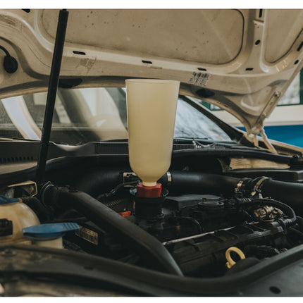 Car engine with a bottle of liquid being added, likely for maintenance.
